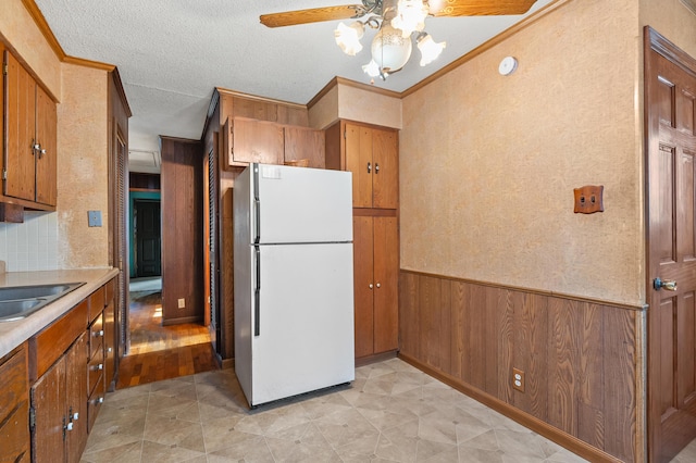 156 N Woodlawn Ave, Battle Creek, MI 49037 - kitchen featuring freestanding refrigerator, brown cabinets, ceiling fan, a wainscoted wall, and light countertops