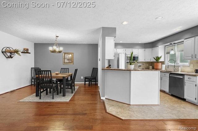 6559 Ridgeview Dr, Clarkston, MI 48346 - kitchen featuring appliances with stainless steel finishes, a chandelier, white cabinetry, light wood-style floors, and a textured ceiling