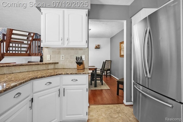 6559 Ridgeview Dr, Clarkston, MI 48346 - kitchen featuring freestanding refrigerator, backsplash, light stone counters, a textured ceiling, and white cabinetry