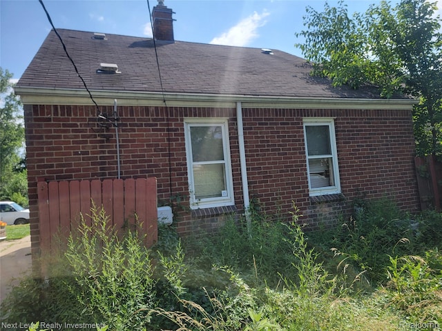 8850 Farmbrook St, Detroit, MI 48236 - view of side of home with brick siding, a chimney, and a shingled roof