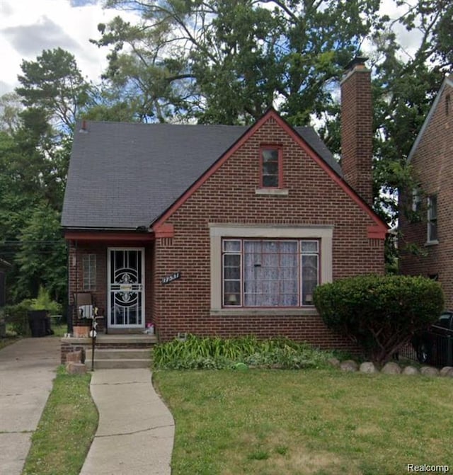 17531 Pinehurst St, Detroit, MI 48221 - tudor house featuring brick siding, a chimney, a front lawn, and a shingled roof