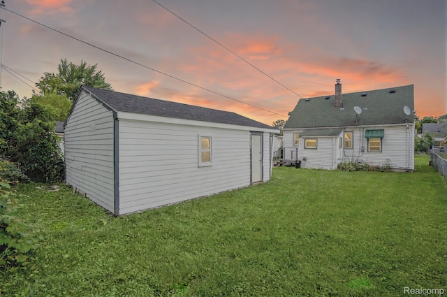 23199 Stewart Ave, Warren, MI 48089 - back of property at dusk with a yard, an outdoor structure, and a chimney
