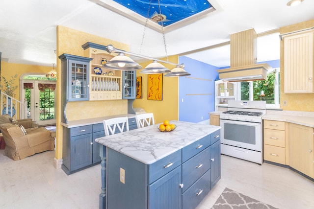 8150 Mester Rd, Chelsea, MI 48118 - kitchen featuring white gas range oven, glass insert cabinets, a center island, pendant lighting, and blue cabinetry
