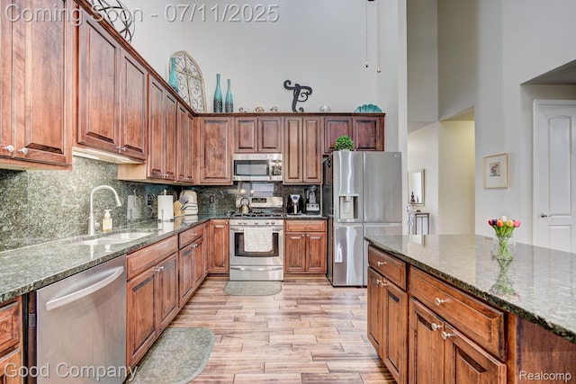 4361 Bennett Park Cir, Troy, MI 48085 - kitchen with appliances with stainless steel finishes, a high ceiling, light wood-type flooring, dark stone counters, and decorative backsplash