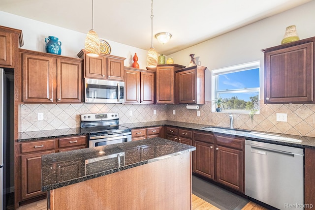 16621 Charles Town Ct, Linden, MI 48451 - kitchen featuring appliances with stainless steel finishes, light wood-style floors, a center island, dark stone counters, and pendant lighting