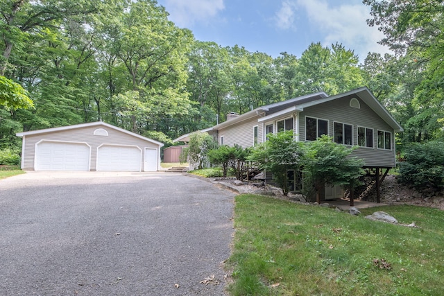 23974 Hooker Dr, Sand Lake, MI 49343 - view of front of property with a garage, an outdoor structure, a chimney, view of scattered trees, and a front lawn