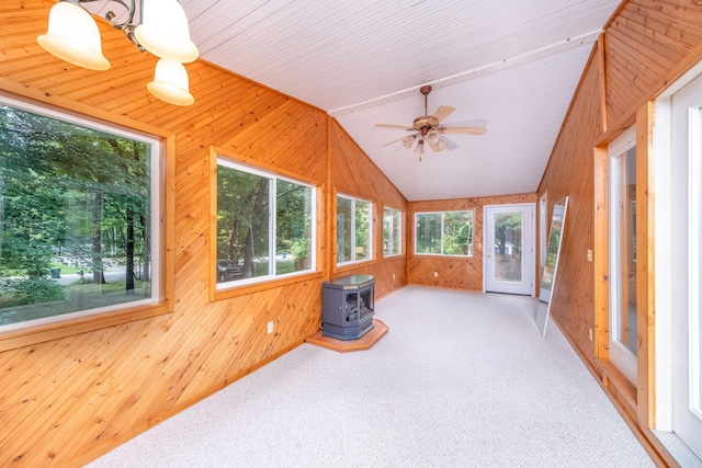 23974 Hooker Dr, Sand Lake, MI 49343 - unfurnished sunroom featuring a wood stove, wood walls, lofted ceiling, and carpet floors