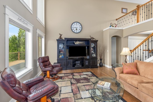 9752 Jackson Rd, Clarksville, MI 48815 - living area with a towering ceiling, wood finished floors, stairway, and arched walkways