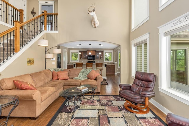 9752 Jackson Rd, Clarksville, MI 48815 - living room with wood finished floors, a high ceiling, arched walkways, and stairs