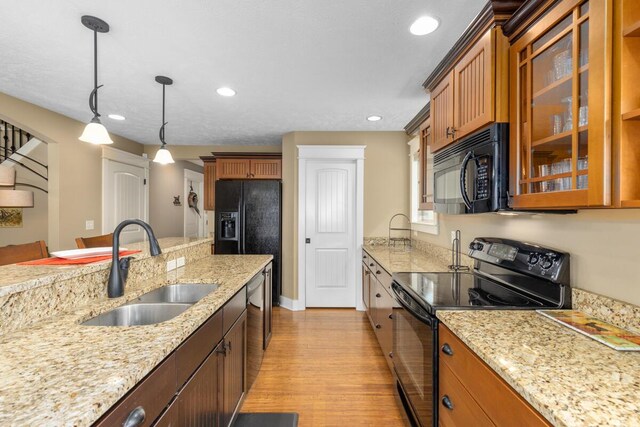 9752 Jackson Rd, Clarksville, MI 48815 - kitchen with black appliances, glass insert cabinets, brown cabinets, light wood-style flooring, and recessed lighting