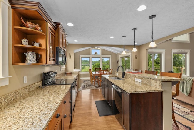 9752 Jackson Rd, Clarksville, MI 48815 - kitchen with a kitchen breakfast bar, black appliances, open shelves, light wood-type flooring, and light stone counters