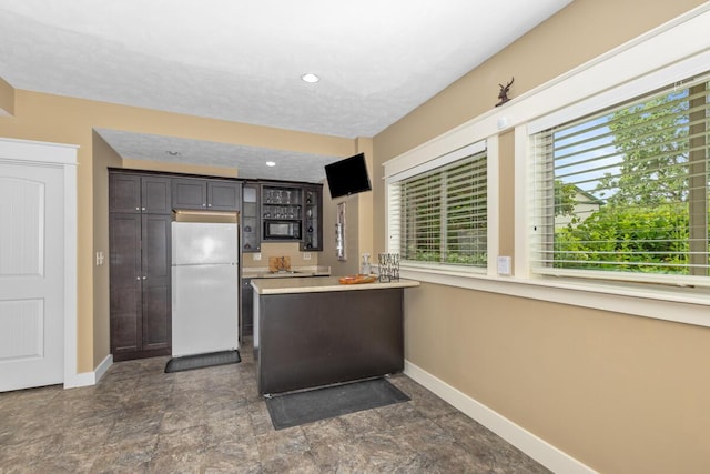 9752 Jackson Rd, Clarksville, MI 48815 - kitchen featuring freestanding refrigerator, black microwave, light countertops, a peninsula, and dark brown cabinets