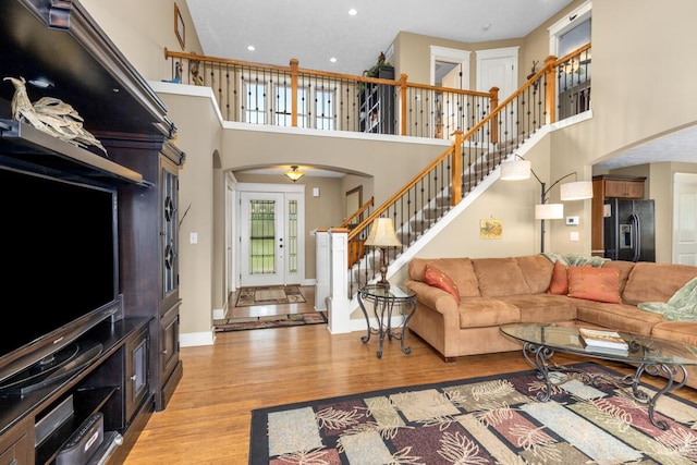 9752 Jackson Rd, Clarksville, MI 48815 - living room with arched walkways, stairway, light wood-style floors, a high ceiling, and recessed lighting