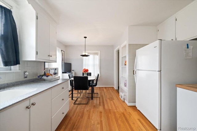 8220 Hartwell St, Detroit, MI 48228 - kitchen with freestanding refrigerator, light wood-style floors, light countertops, white cabinets, and tasteful backsplash