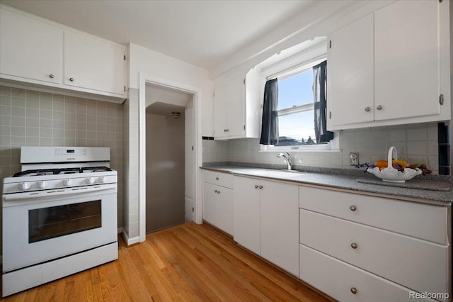 8220 Hartwell St, Detroit, MI 48228 - kitchen featuring gas range gas stove, decorative backsplash, light wood finished floors, white cabinets, and light countertops