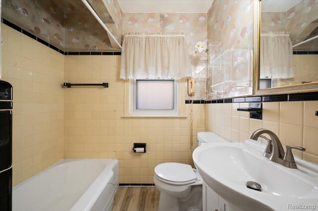 8220 Hartwell St, Detroit, MI 48228 - full bathroom featuring wood finished floors, tile walls, a tub to relax in, vanity, and wallpapered walls