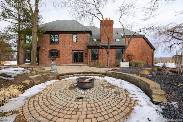 1180 Knob Creek Dr, Rochester, MI 48306 - snow covered rear of property with brick siding, a chimney, a fire pit, and a patio