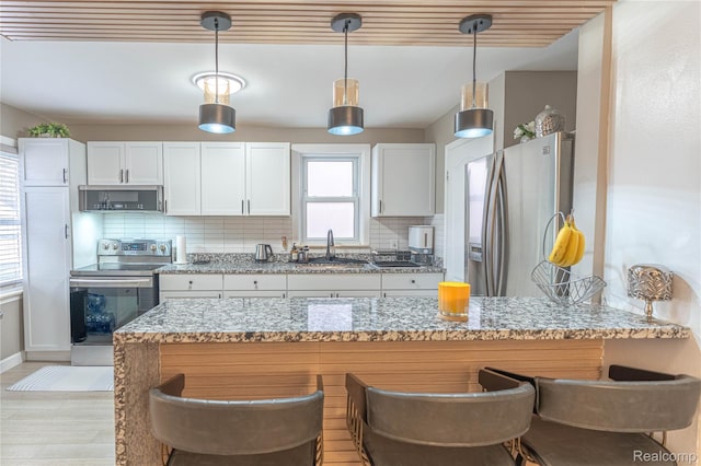 2544 S Beatrice St, Detroit, MI 48217 - kitchen featuring stainless steel appliances, decorative backsplash, light stone countertops, and white cabinetry