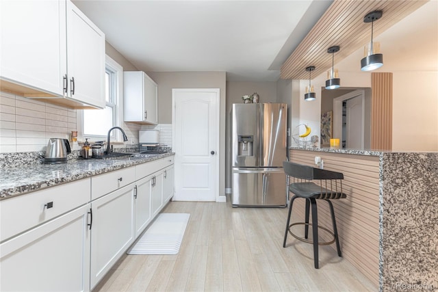 2544 S Beatrice St, Detroit, MI 48217 - kitchen featuring stainless steel fridge, decorative backsplash, light wood-type flooring, light stone counters, and white cabinets