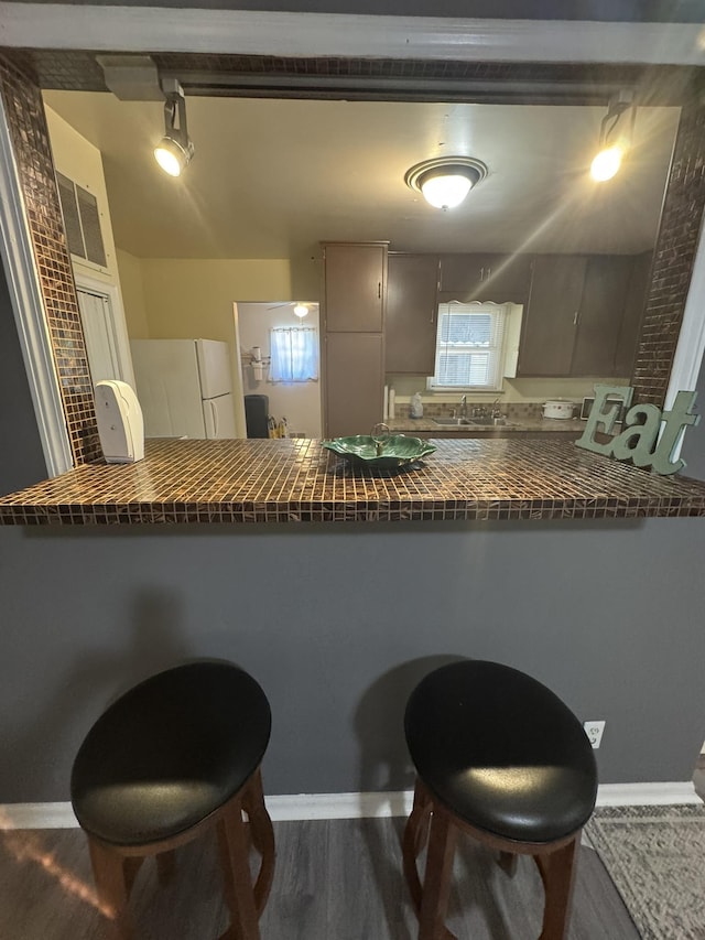 3355 Lyndon Ave, Flint, MI 48504 - kitchen featuring dark countertops, freestanding refrigerator, a peninsula, wood finished floors, and track lighting