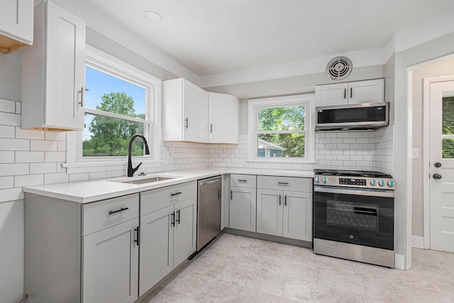 1816 Jennette Ave NW, Grand Rapids, MI 49504 - kitchen featuring appliances with stainless steel finishes, light countertops, decorative backsplash, and white cabinets
