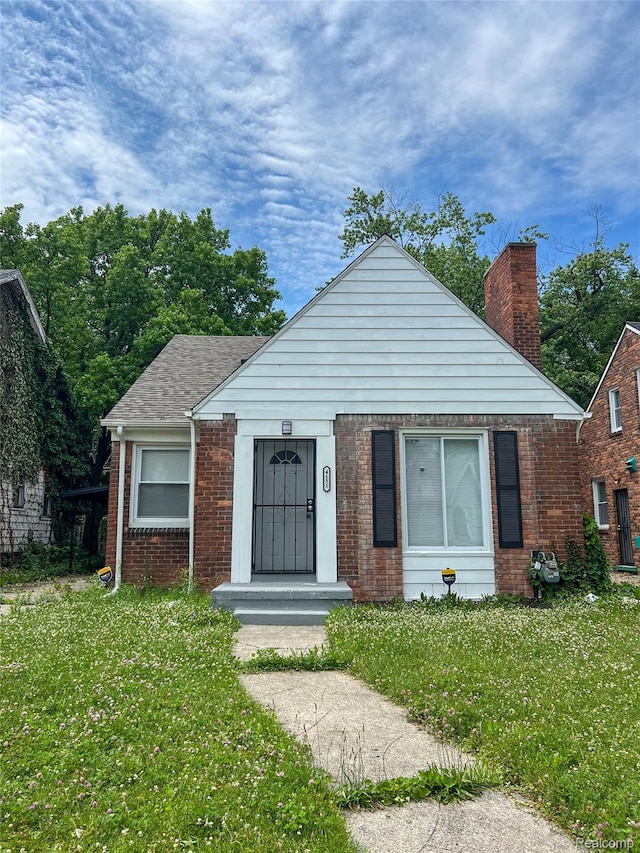 4651 Berkshire St, Detroit, MI 48224 - bungalow-style home with brick siding, a front lawn, and a chimney