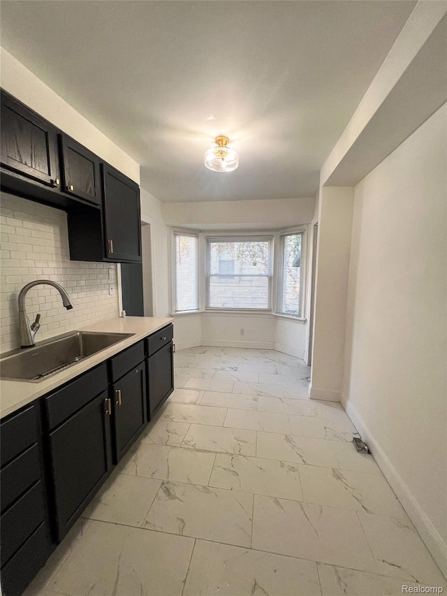 4651 Berkshire St, Detroit, MI 48224 - kitchen with light marble finish floors, dark cabinetry, light countertops, and decorative backsplash