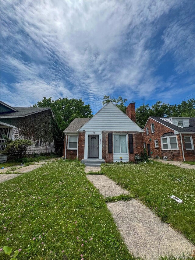 4651 Berkshire St, Detroit, MI 48224 - bungalow-style house with brick siding, a front yard, and a chimney