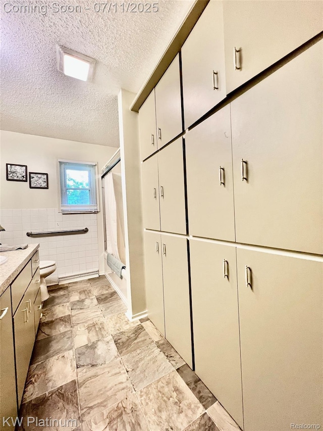 3775 Carrigan Rd, Fort Gratiot, MI 48059 - full bath with a textured ceiling, vanity, tile walls, a shower with door, and a wainscoted wall