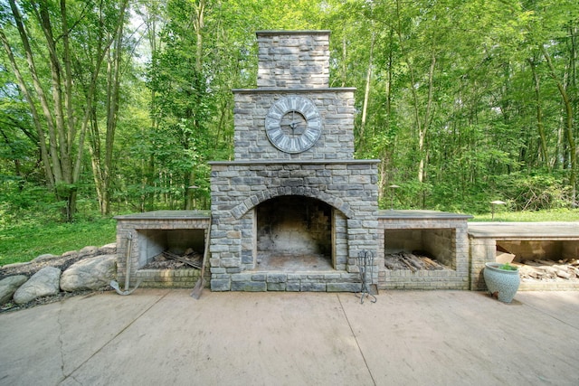 8395 Dalton Rd, Onsted, MI 49265 - view of patio / terrace with an outdoor stone fireplace and a forest view
