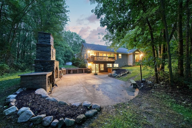 8395 Dalton Rd, Onsted, MI 49265 - back of property at dusk featuring an outdoor stone fireplace, a patio area, a chimney, and a deck