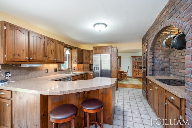 1214 Euna Vista Dr, Holland, MI 49423 - kitchen featuring appliances with stainless steel finishes, a peninsula, light countertops, a breakfast bar area, and brown cabinets