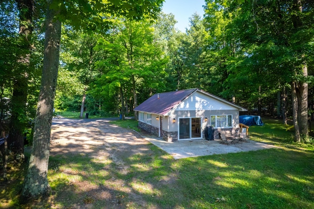 11901 187th Ave, Stanwood, MI 49346 - rear view of house featuring a lawn, a patio, a metal roof, and a view of trees