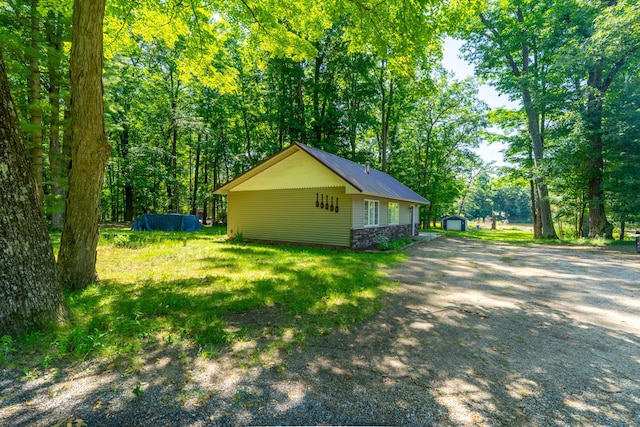 11901 187th Ave, Stanwood, MI 49346 - view of home's exterior with stone siding, a metal roof, and a storage shed