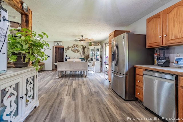 9265 Mulliken Rd, Mulliken, MI 48861 - kitchen with stainless steel appliances, light wood-style floors, light countertops, a textured ceiling, and a ceiling fan