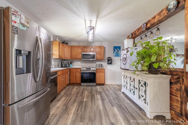 9265 Mulliken Rd, Mulliken, MI 48861 - kitchen featuring appliances with stainless steel finishes, a textured ceiling, light countertops, and light wood finished floors