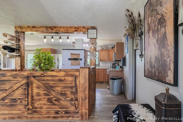 9265 Mulliken Rd, Mulliken, MI 48861 - kitchen featuring wood finished floors, a textured ceiling, light countertops, freestanding refrigerator, and brown cabinetry