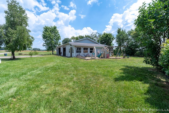 9265 Mulliken Rd, Mulliken, MI 48861 - rear view of property featuring a lawn and a playground