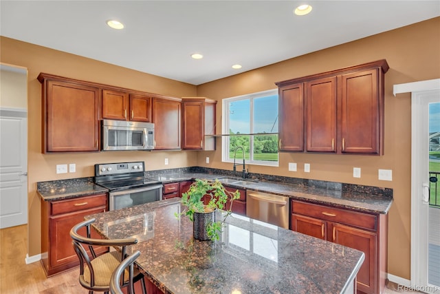 6119 Amber Ln, Grand Blanc, MI 48439 - kitchen with stainless steel appliances, recessed lighting, a center island, dark stone counters, and light wood-style floors