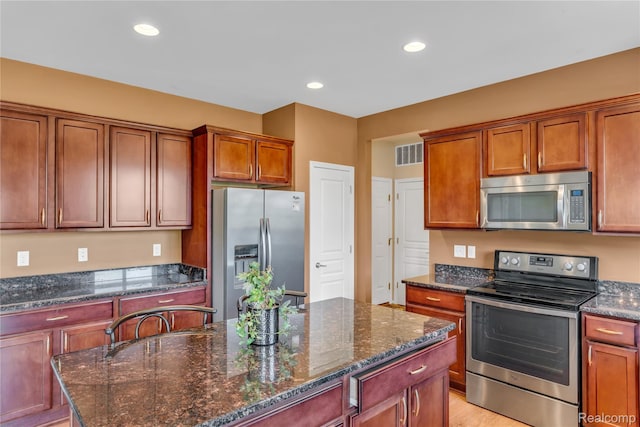 6119 Amber Ln, Grand Blanc, MI 48439 - kitchen featuring appliances with stainless steel finishes, a kitchen island, dark stone counters, recessed lighting, and brown cabinets