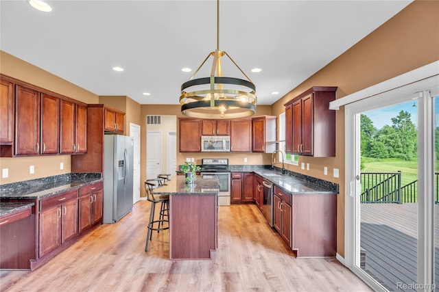 6119 Amber Ln, Grand Blanc, MI 48439 - kitchen featuring appliances with stainless steel finishes, a chandelier, dark stone countertops, a breakfast bar, and light wood-style flooring