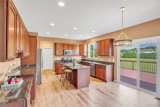 6119 Amber Ln, Grand Blanc, MI 48439 - kitchen featuring stainless steel appliances, a breakfast bar, brown cabinets, light wood-style floors, and a kitchen island