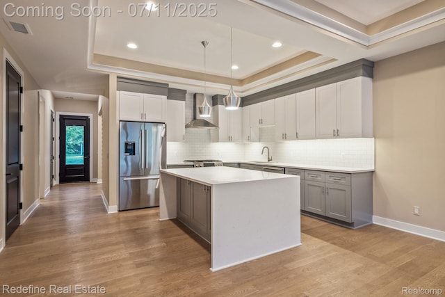 722 E Parent Ave, Royal Oak, MI 48067 - kitchen with stainless steel fridge, a tray ceiling, wall chimney exhaust hood, a center island, and tasteful backsplash