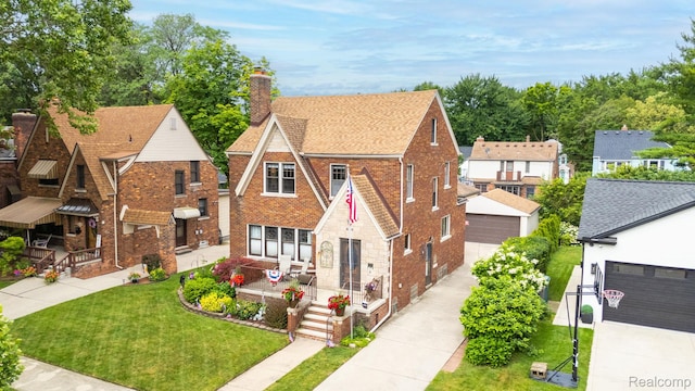 648 S Highland St, Dearborn, MI 48124 - english style home featuring a front yard, brick siding, a chimney, a porch, and a detached garage