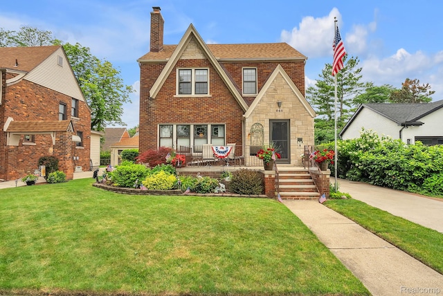 648 S Highland St, Dearborn, MI 48124 - tudor-style house featuring a chimney, a front lawn, brick siding, and a shingled roof