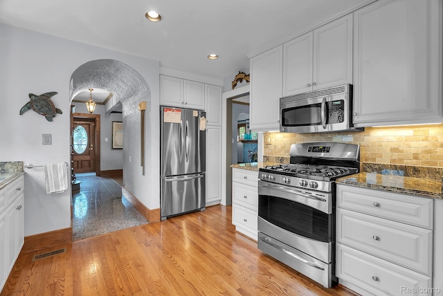 648 S Highland St, Dearborn, MI 48124 - kitchen with appliances with stainless steel finishes, white cabinets, decorative backsplash, arched walkways, and recessed lighting