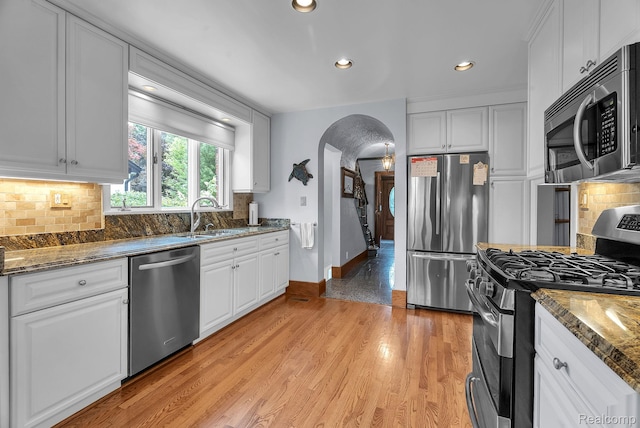 648 S Highland St, Dearborn, MI 48124 - kitchen with appliances with stainless steel finishes, decorative backsplash, arched walkways, white cabinetry, and recessed lighting