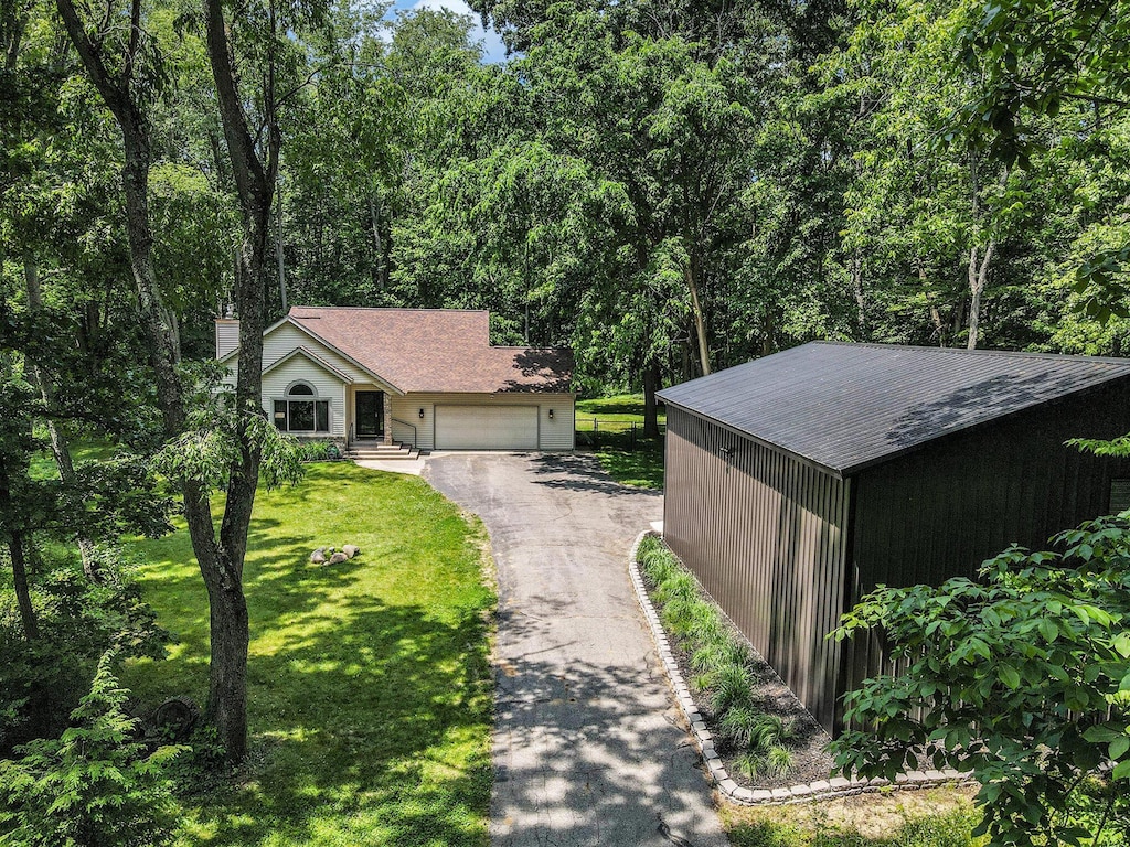 1355 N 7th St, Kalamazoo, MI 49009 - view of front of home with a front yard, asphalt driveway, a garage, and a view of trees