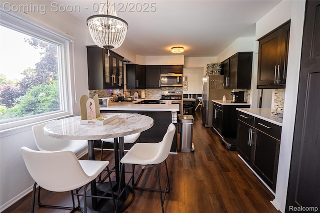 42331 Beacontree Ct, Northville, MI 48168 - kitchen with appliances with stainless steel finishes, decorative backsplash, light countertops, a chandelier, and glass insert cabinets