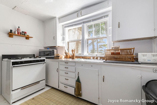 5752 E 52nd St, Newaygo, MI 49337 - kitchen featuring white gas range, stainless steel microwave, white cabinets, light countertops, and light flooring